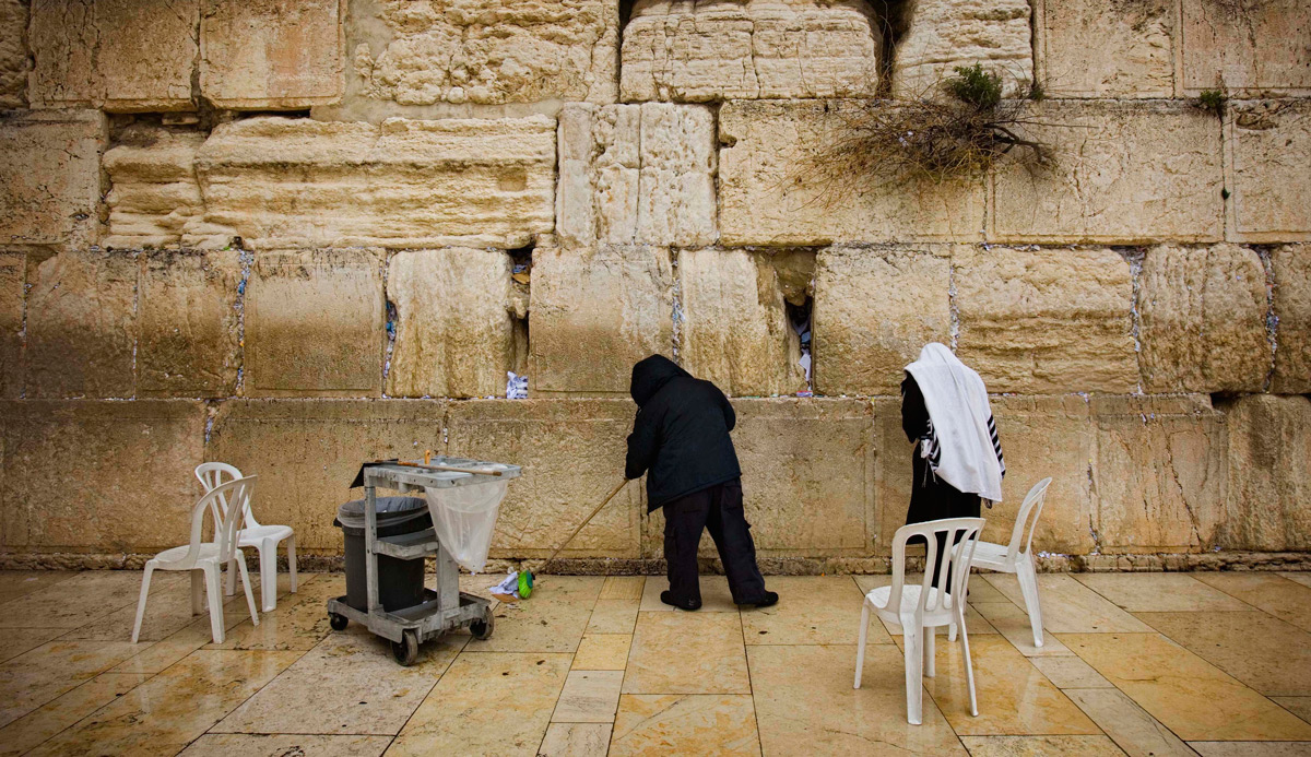A haredi man prays as a man sweeps the floor next to the Western Wall in Jerusalem. AP Photo/Bernat Armangue.

