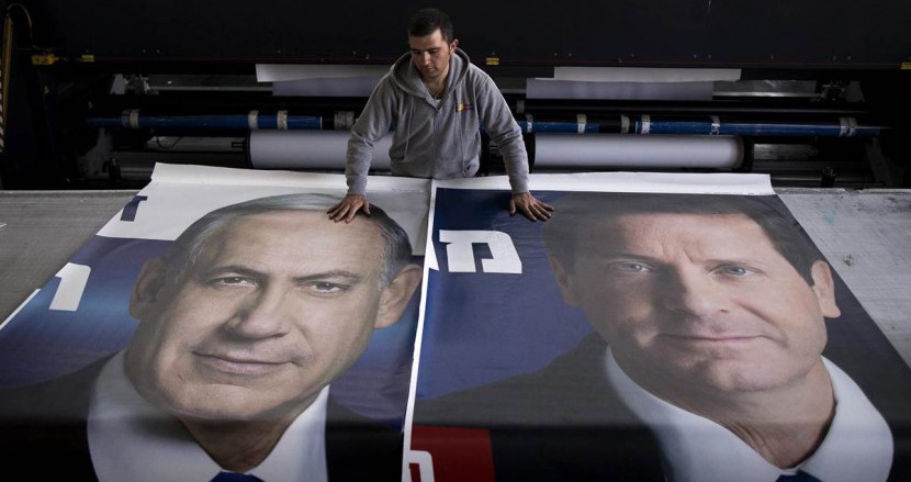 A worker lays out posters of Benjamin Netanyahu and Isaac Herzog during the 2015 Israeli election campaign.

