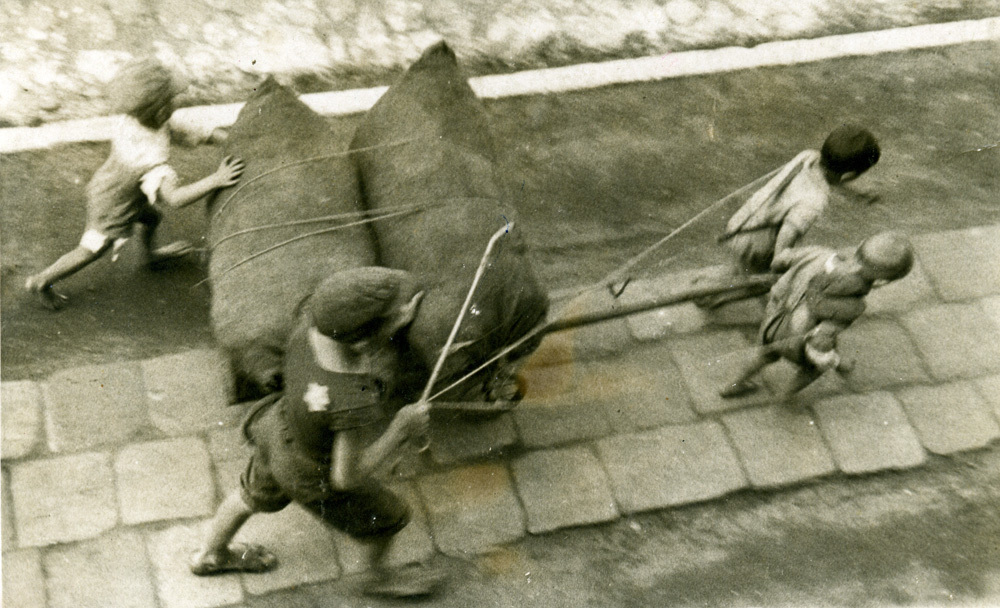 Jewish children pulling a cart with two bags in the Łódź ghetto.
