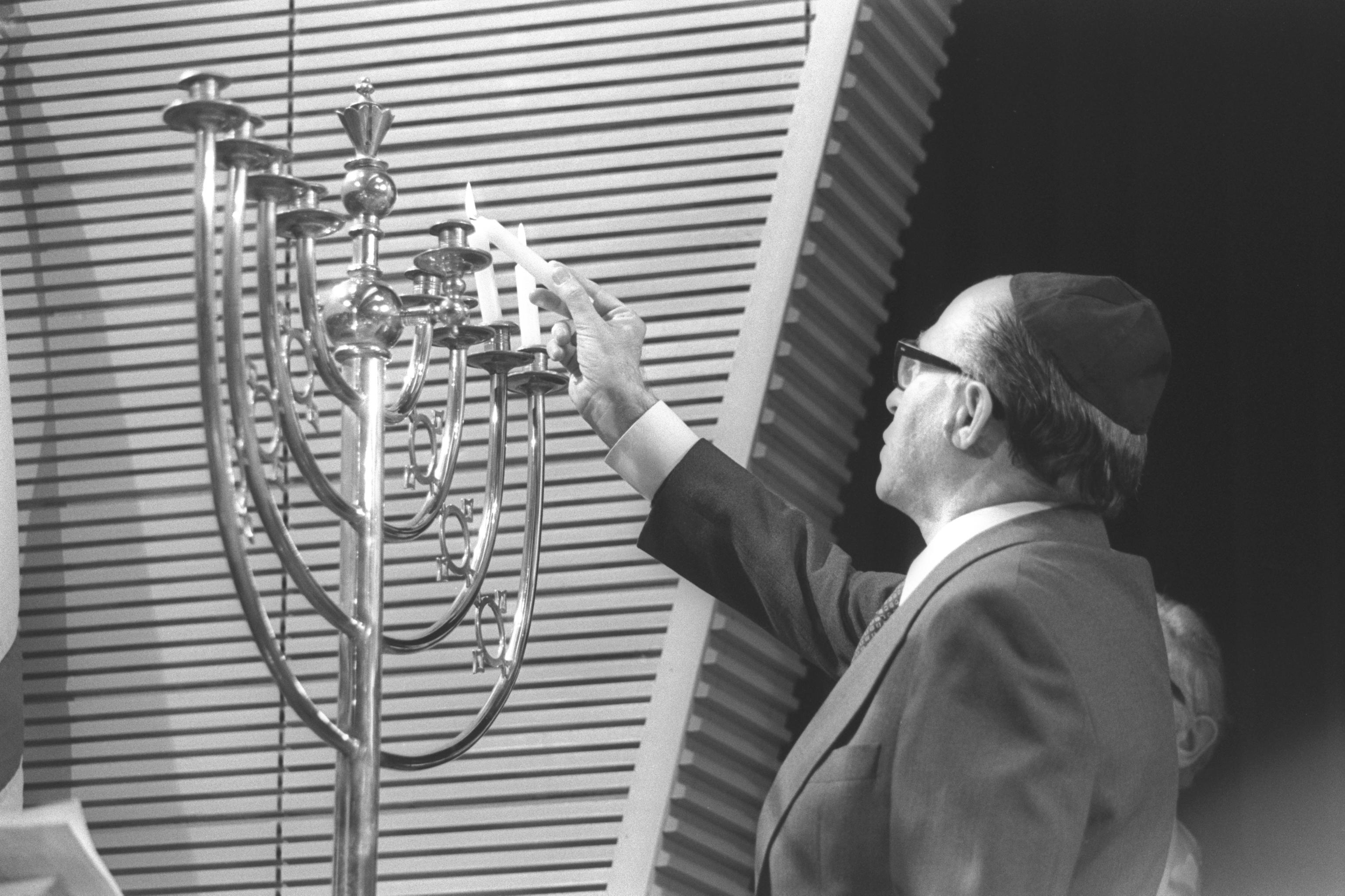 Menachem Begin lighting Hanukkah candles in St John&#8217;s Wood Synagogue, London on December 1, 1977. Saar Yaacov/Government Press Office.

