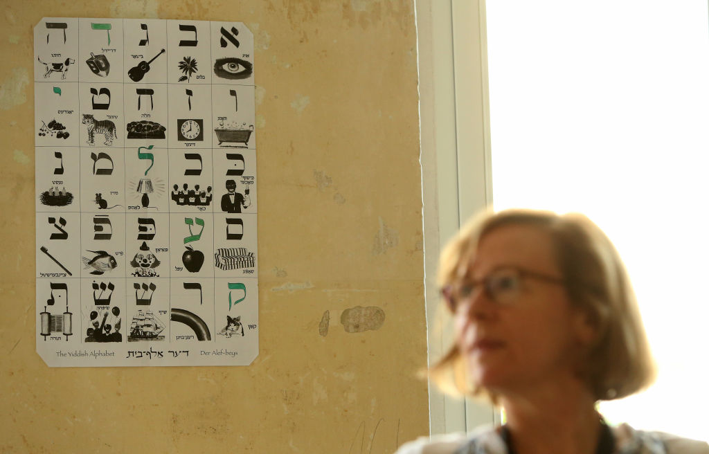 In Germany, a student takes part in a course taught as part of the Yiddish Summer Weimar of 2018, a summer institute and festival focused on Yiddish, while a Yiddish alphabet hangs on the wall. Photo by Adam Berry/Getty Images.
