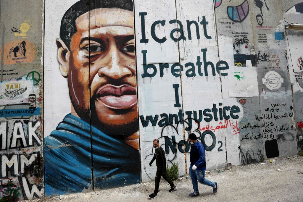 People walk past a mural of George Floyd on March 31, 2021, painted on a section of Israel&#8217;s separation barrier in the city of Bethlehem. Photo by Emmanuel Dunand/AFP via Getty Images.
