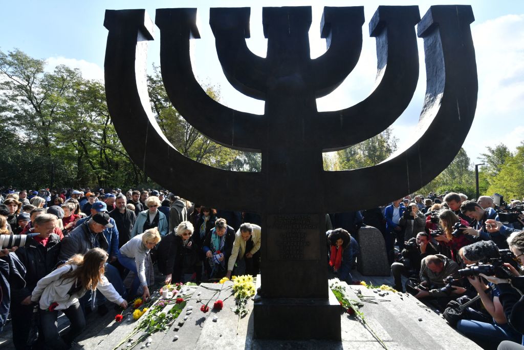People lay symbolic stones and flowers at the Babi Yar Holocaust Memorial in Kyiv, Ukraine, on September 29, 2019. Photo by SERGEI SUPINSKY/AFP via Getty Images. 
