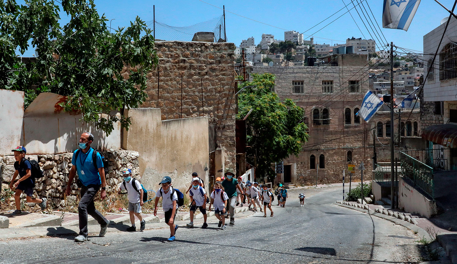 Israeli settlers with children walk in the city of Hebron on June 30, 2020. HAZEM BADER/AFP via Getty Images.
