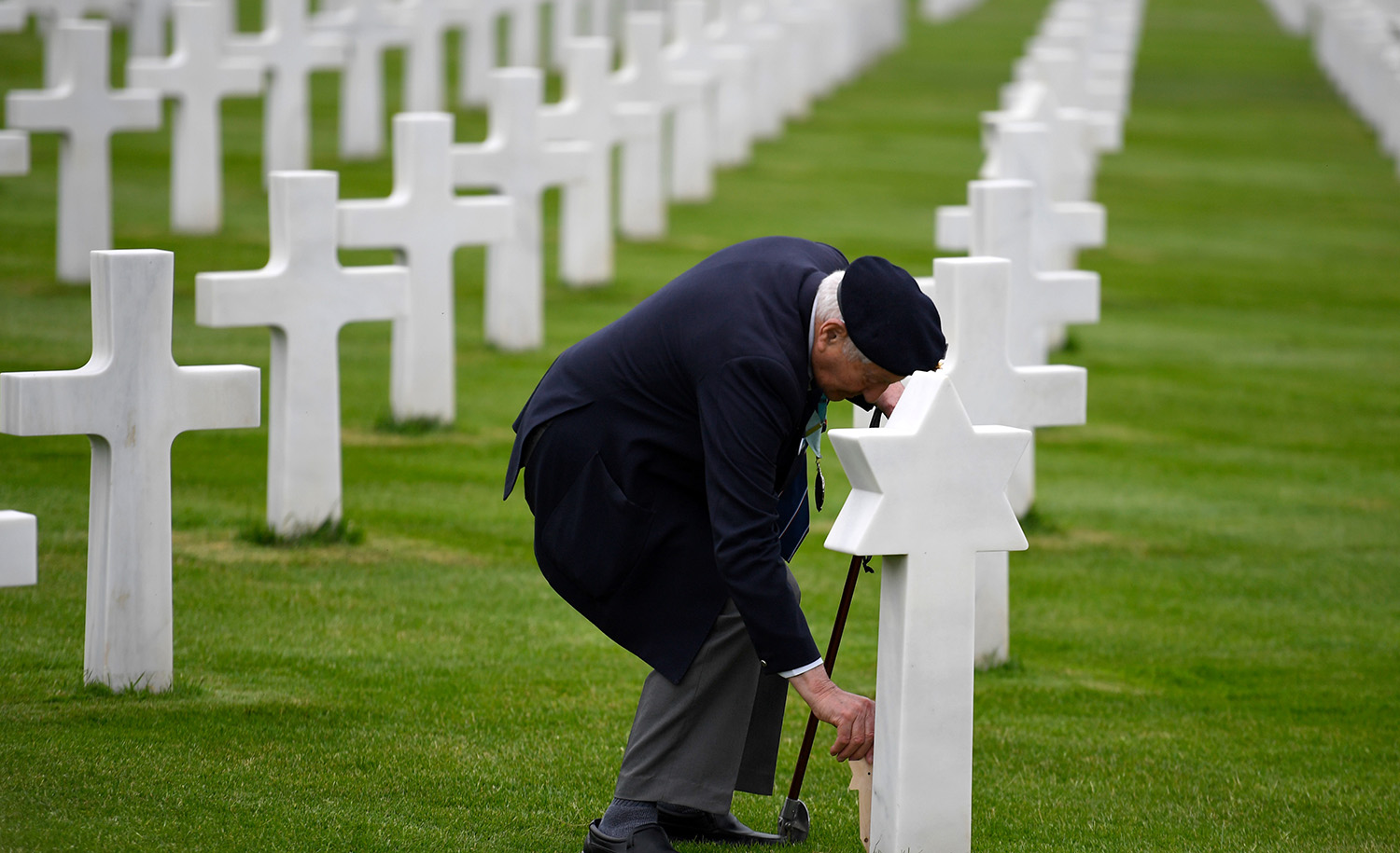 WWII veteran Mervyn Kresh places a poppy on an inscribed wooden star of David by a headstone after a remembrance ceremony at the Normandy American Cemetery in Colleville-sur-Mer on June 4, 2019, ahead of the 75th anniversary of D-Day. DAMIEN MEYER/AFP via Getty Images.
