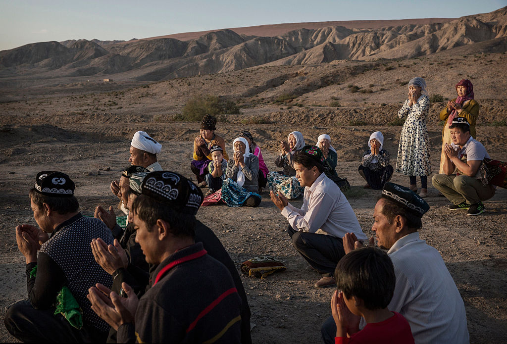 A Uighur family prays at the grave of a loved one on September 12, 2016 at a local shrine and cemetery in Turpan County, in the far western Xinjiang province, China. Photo by Kevin Frayer via Getty Images.
