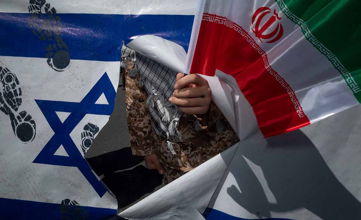 
A member of Iran&#8217;s Basij paramilitary force holds an Iranian flag while standing behind a torn Israeli flag during a rally commemorating International Quds Day in downtown Tehran, April 14, 2023. Morteza Nikoubazl/NurPhoto via Getty Images.






