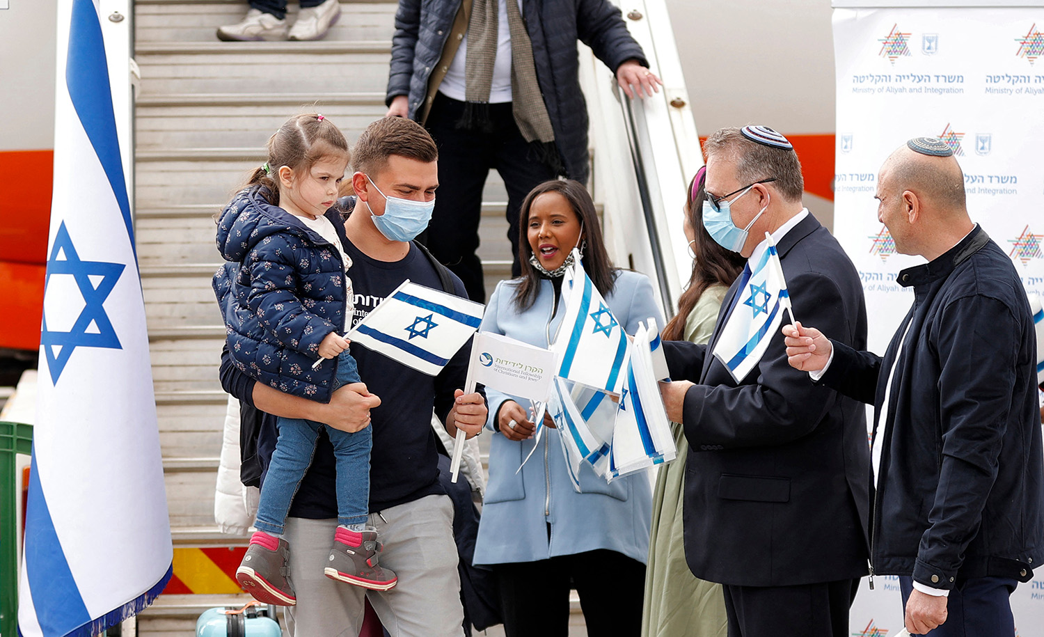 
Pnina Tamano-Shata, Israel&#8217;s Minister of Immigration and Absorption, and Yaakov Hagoel, head of the World Zionist Organization, hand out Israeli flags to immigrants from Ukraine at Ben-Gurion Airport in Lod on February 20, 2022. JACK GUEZ / AFP) (Photo by JACK GUEZ/AFP via Getty Images.






