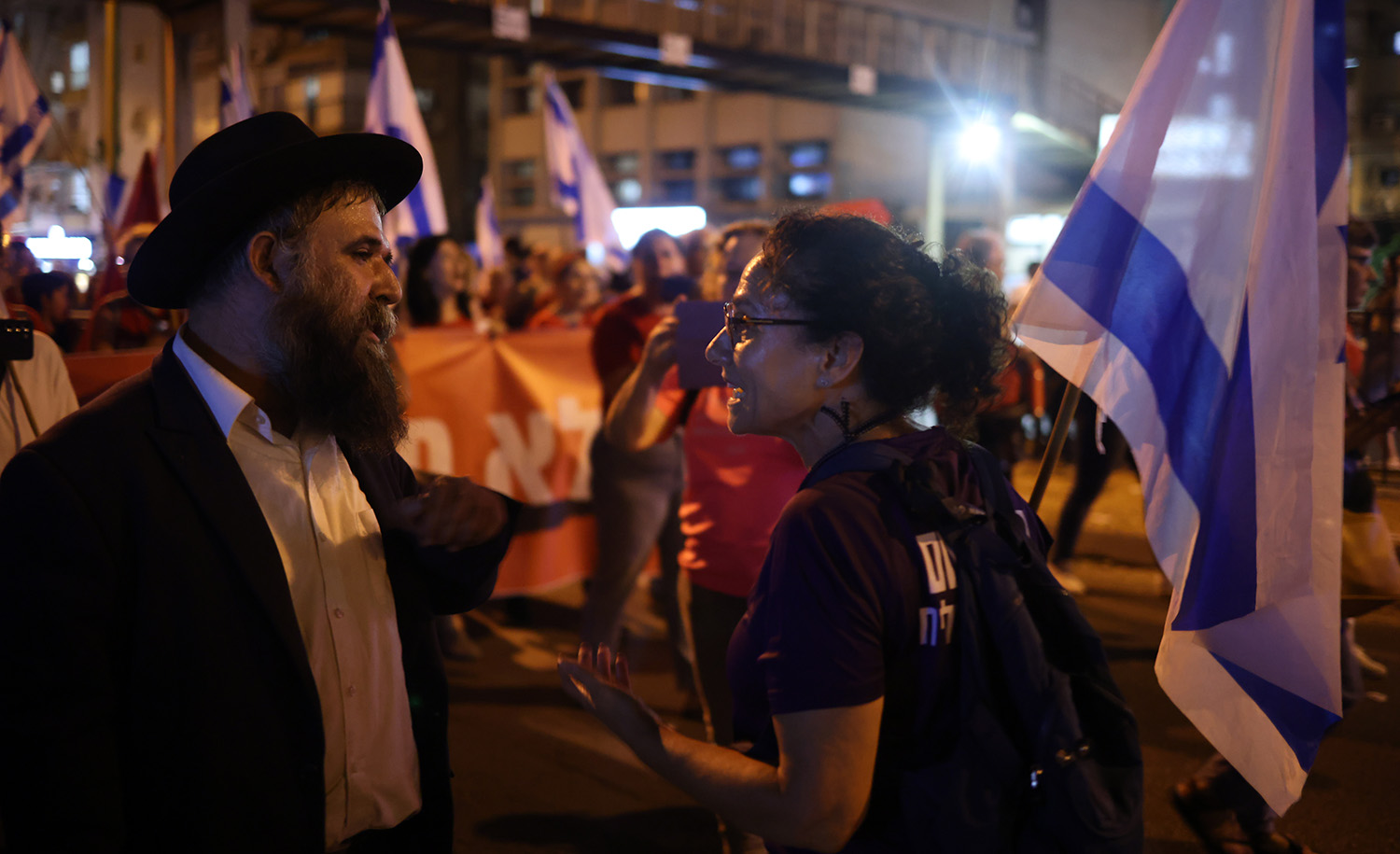 


An anti-government activist talks with an ultra-Orthodox man during a protest in Bnei Brak, Israel, on August 24, 2023. Oren Ziv/picture alliance via Getty Images.













