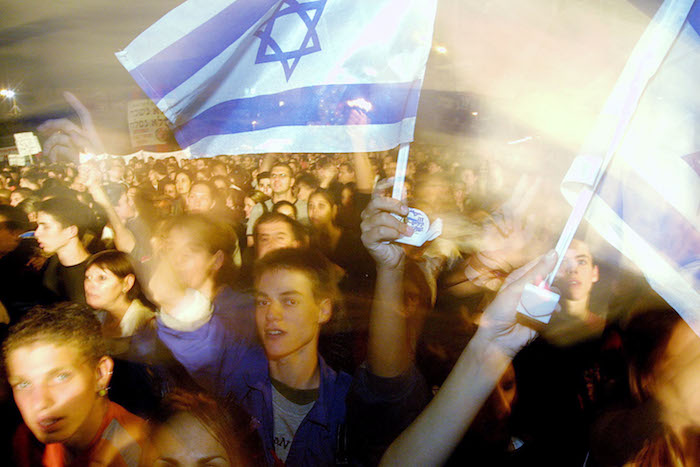 Demonstrators sing peace songs during a rally in Tel Aviv in 2002. Quique Kierszenbaum/Getty Images.